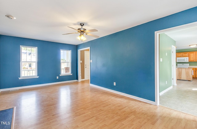 empty room with baseboards, visible vents, ceiling fan, and light wood finished floors