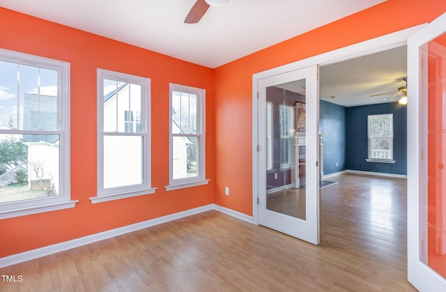 empty room with baseboards, ceiling fan, and light wood-style floors