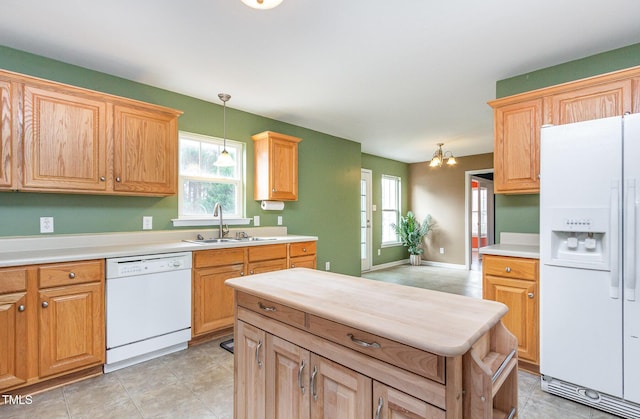 kitchen featuring light countertops, white appliances, a sink, and decorative light fixtures