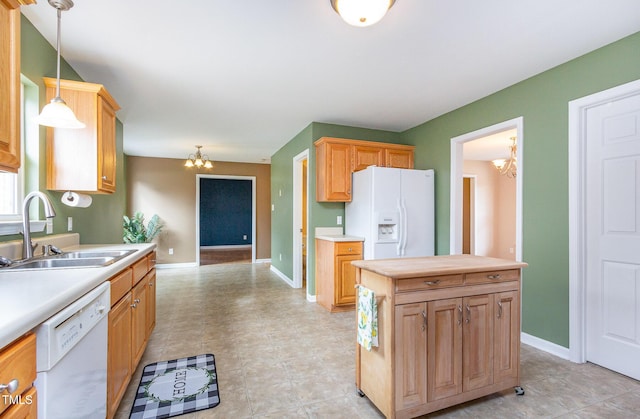 kitchen with a chandelier, white appliances, a sink, light countertops, and hanging light fixtures