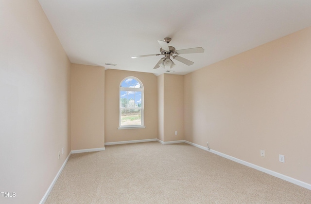 spare room with ceiling fan, visible vents, baseboards, and light colored carpet