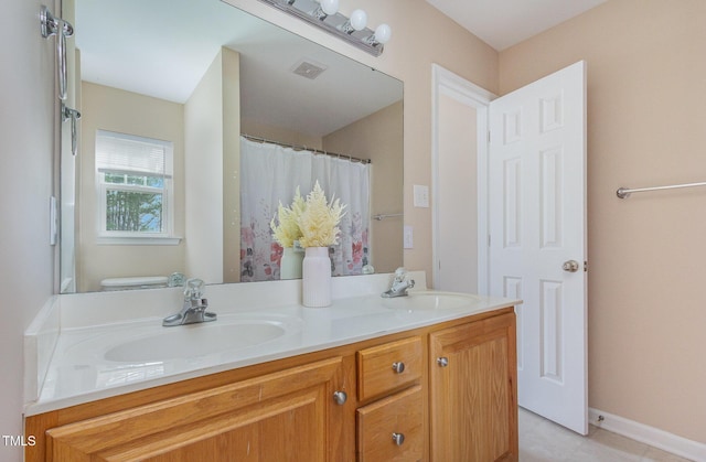 bathroom featuring visible vents, a sink, baseboards, and double vanity