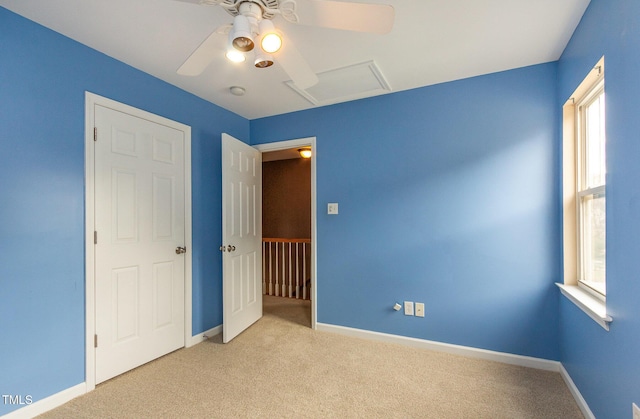 unfurnished bedroom with carpet floors, attic access, baseboards, and a ceiling fan