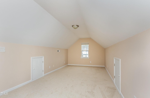 bonus room with lofted ceiling, light carpet, and baseboards