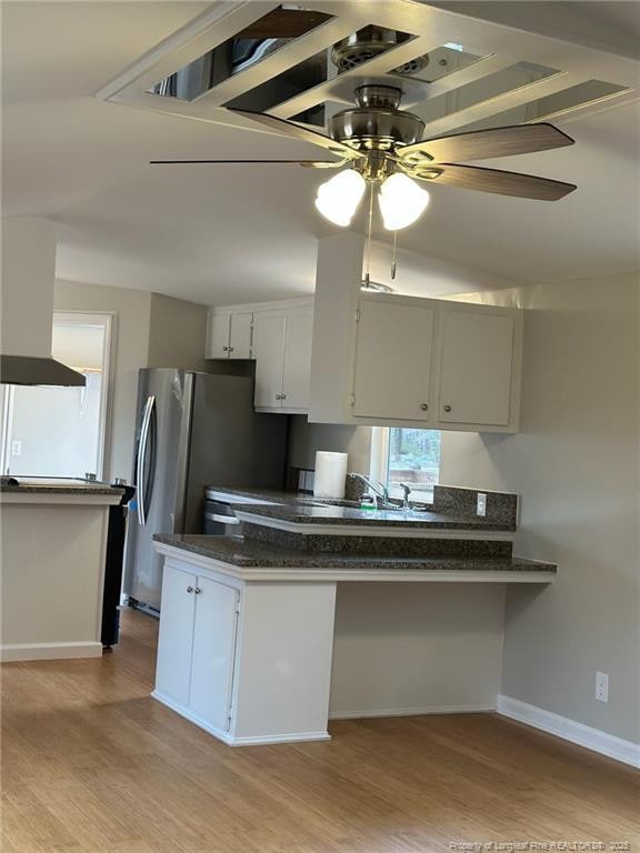 kitchen with ceiling fan, a peninsula, white cabinetry, baseboards, and light wood-type flooring