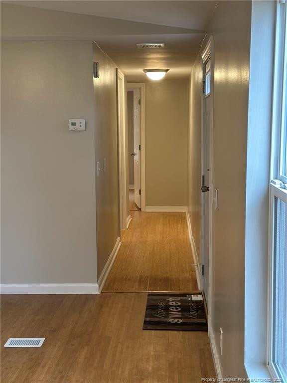 hallway featuring baseboards, visible vents, and wood finished floors