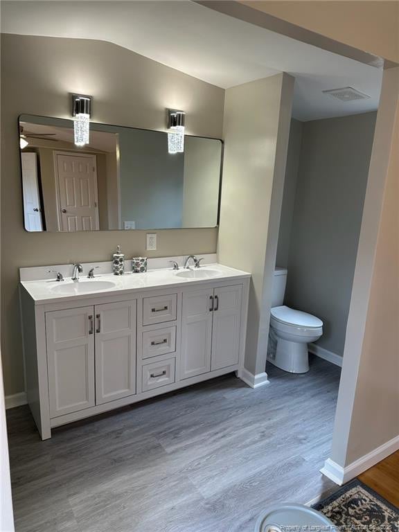 bathroom with baseboards, a sink, toilet, and wood finished floors