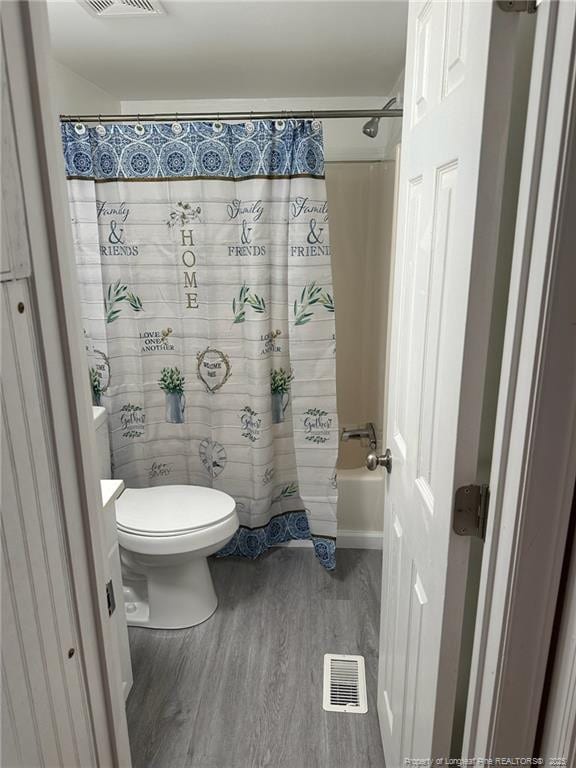 full bathroom with visible vents, shower / tub combo with curtain, toilet, and wood finished floors