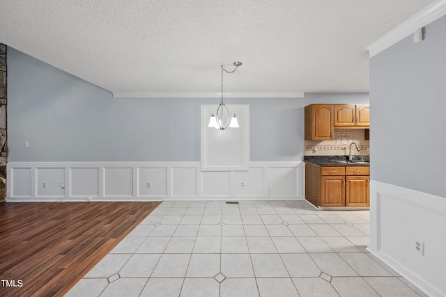 interior space featuring light hardwood / wood-style flooring, a notable chandelier, a textured ceiling, ornamental molding, and sink