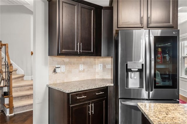 kitchen with dark wood-type flooring, backsplash, dark brown cabinetry, light stone countertops, and stainless steel fridge with ice dispenser