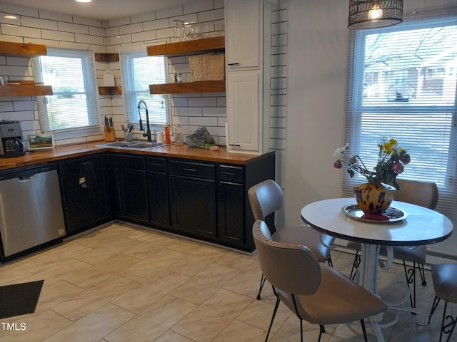 kitchen featuring wood counters, sink, decorative backsplash, and stainless steel dishwasher