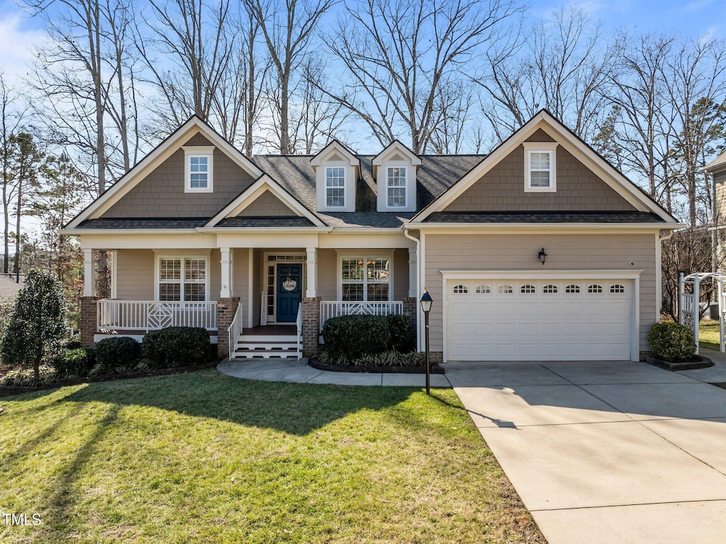 craftsman inspired home featuring driveway, a shingled roof, an attached garage, covered porch, and a front lawn