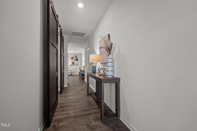 corridor featuring a barn door and dark wood-type flooring