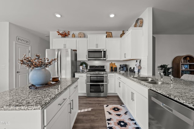 kitchen featuring appliances with stainless steel finishes, light stone countertops, sink, and white cabinets