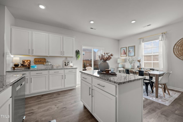 kitchen featuring light stone counters, dishwasher, and white cabinets