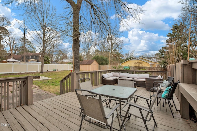 wooden terrace featuring a storage unit, a fenced backyard, an outdoor structure, and outdoor lounge area