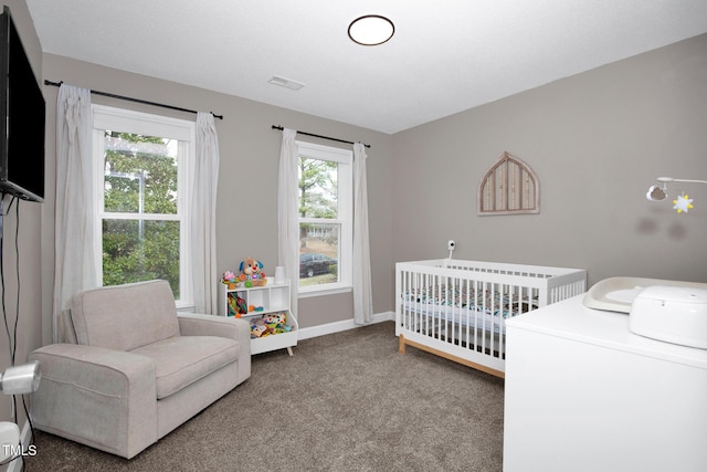 carpeted bedroom featuring visible vents, a crib, and baseboards