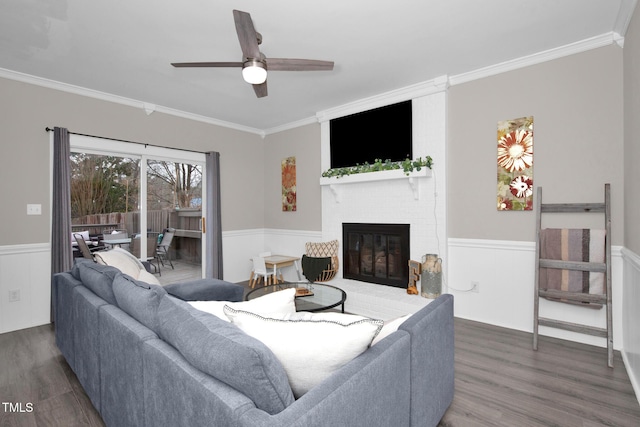 living area featuring a wainscoted wall, ornamental molding, and wood finished floors