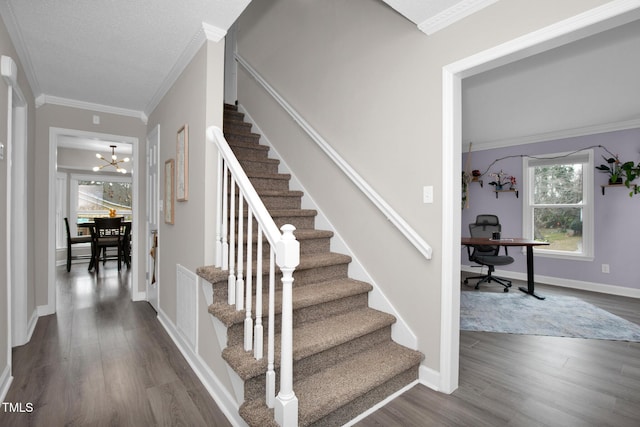 stairs with visible vents, a notable chandelier, wood finished floors, crown molding, and baseboards