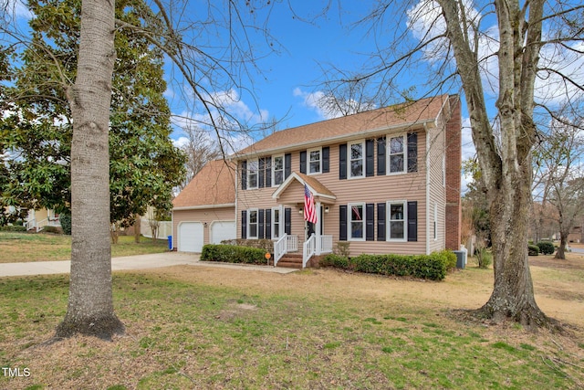 colonial home with a front lawn, a garage, driveway, and roof with shingles