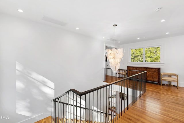 corridor featuring an inviting chandelier, visible vents, wood finished floors, and recessed lighting