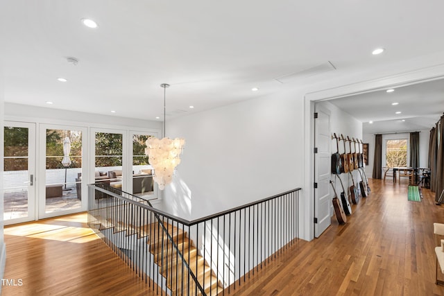 corridor featuring an upstairs landing, wood finished floors, and recessed lighting