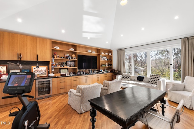 living area featuring light wood-type flooring, wine cooler, a high ceiling, a bar, and recessed lighting