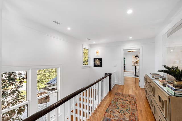 corridor with a wealth of natural light, light wood-style flooring, an upstairs landing, and recessed lighting