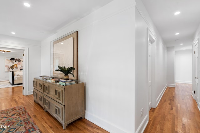 hall featuring light wood-style floors, baseboards, and recessed lighting