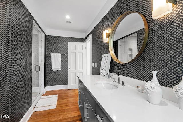 full bath with a shower stall, vanity, wood finished floors, baseboards, and wallpapered walls