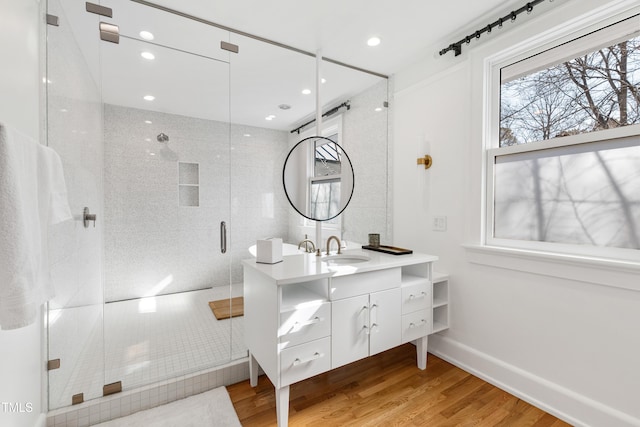 full bath featuring recessed lighting, a shower stall, vanity, wood finished floors, and baseboards