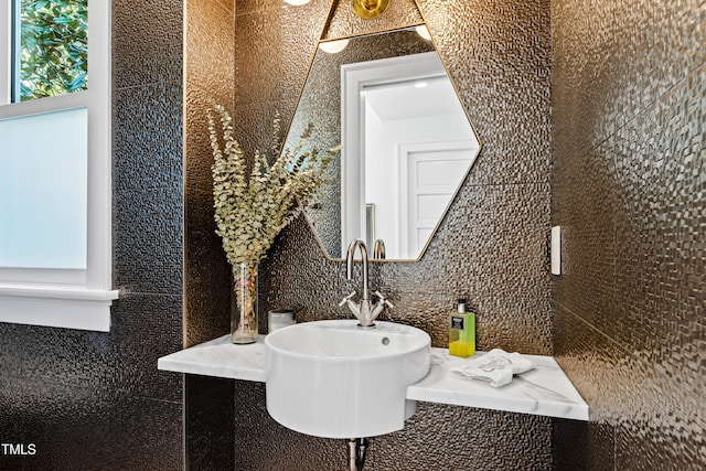 bathroom featuring a sink and tile walls