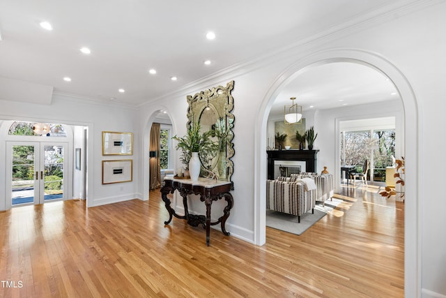 interior space featuring arched walkways, french doors, light wood finished floors, and plenty of natural light