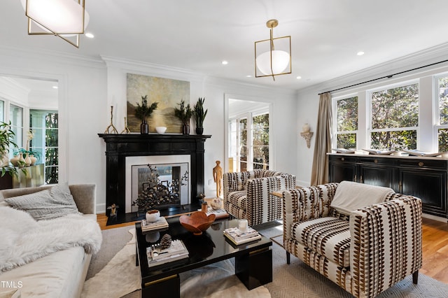 living area featuring a fireplace with flush hearth, recessed lighting, light wood-style floors, and ornamental molding