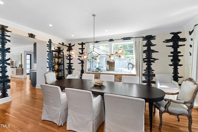 dining area with crown molding, recessed lighting, light wood-type flooring, and an inviting chandelier