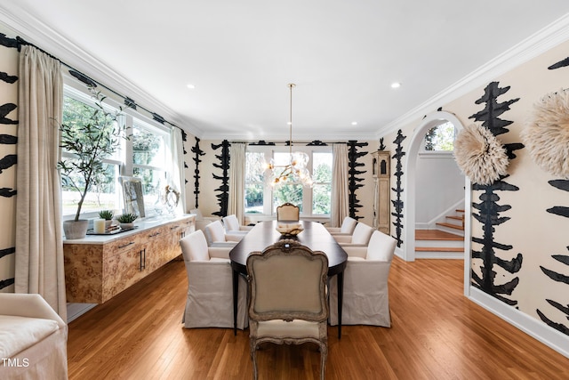 dining area featuring light wood-type flooring, an inviting chandelier, plenty of natural light, and crown molding