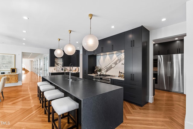 kitchen with recessed lighting, backsplash, appliances with stainless steel finishes, a sink, and dark cabinets