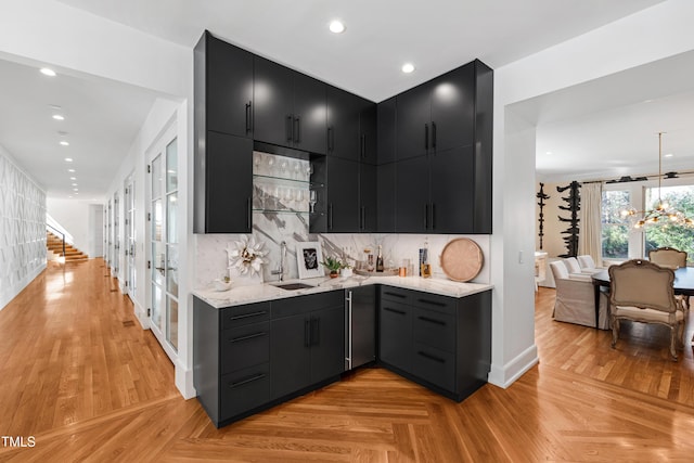 kitchen with tasteful backsplash, light stone counters, dark cabinets, a sink, and recessed lighting