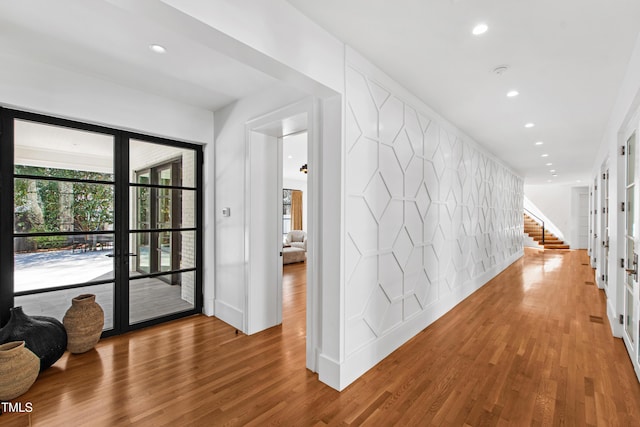 hall featuring recessed lighting, an accent wall, wood finished floors, french doors, and stairway