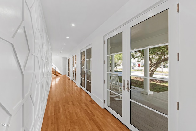 hall featuring light wood-type flooring, recessed lighting, stairs, and french doors