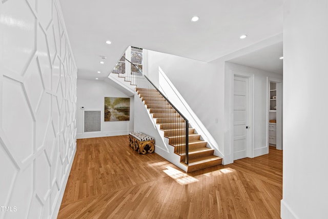 staircase featuring baseboards, wood finished floors, and recessed lighting