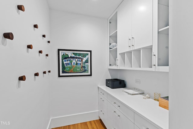 interior space with light wood-style flooring, baseboards, white cabinets, and light countertops