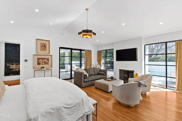 interior space with lofted ceiling, light wood-style flooring, recessed lighting, access to exterior, and a glass covered fireplace