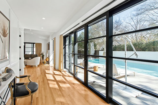 doorway featuring vaulted ceiling, light wood-style flooring, and recessed lighting