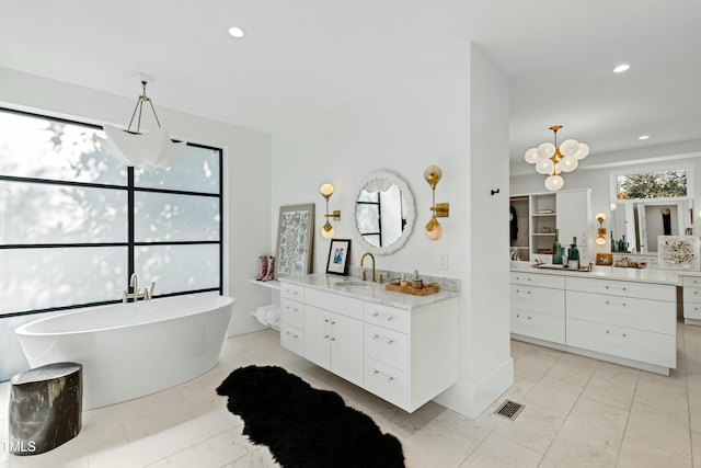 full bathroom featuring recessed lighting, two vanities, visible vents, a freestanding bath, and a sink