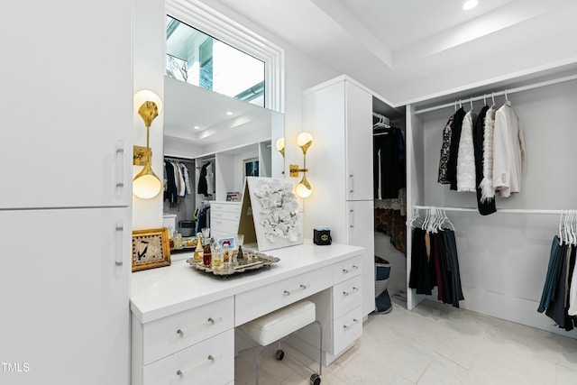 spacious closet with marble finish floor and a tray ceiling