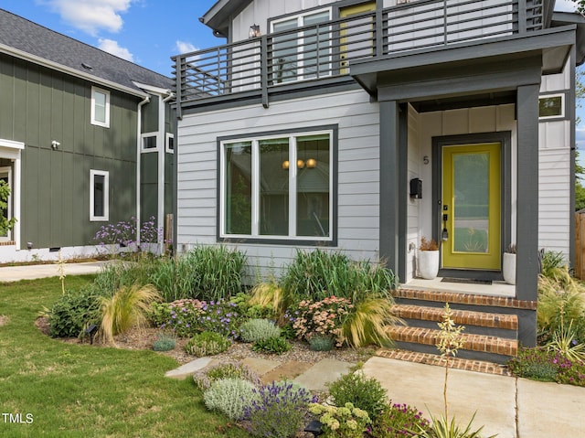 entrance to property featuring a lawn and a balcony