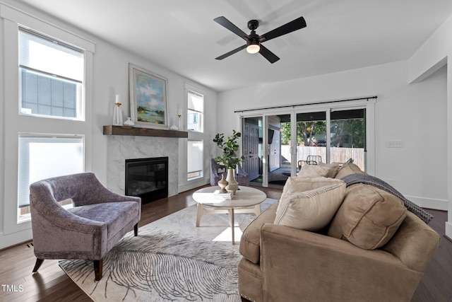 living room featuring ceiling fan, a high end fireplace, and wood-type flooring