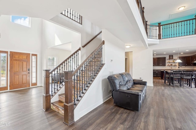 entrance foyer with stairs, a high ceiling, dark wood-style flooring, and baseboards