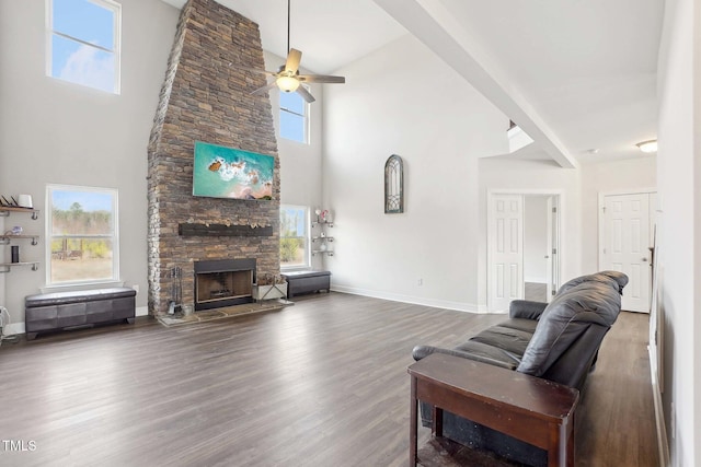 living area with a fireplace, a high ceiling, ceiling fan, wood finished floors, and baseboards